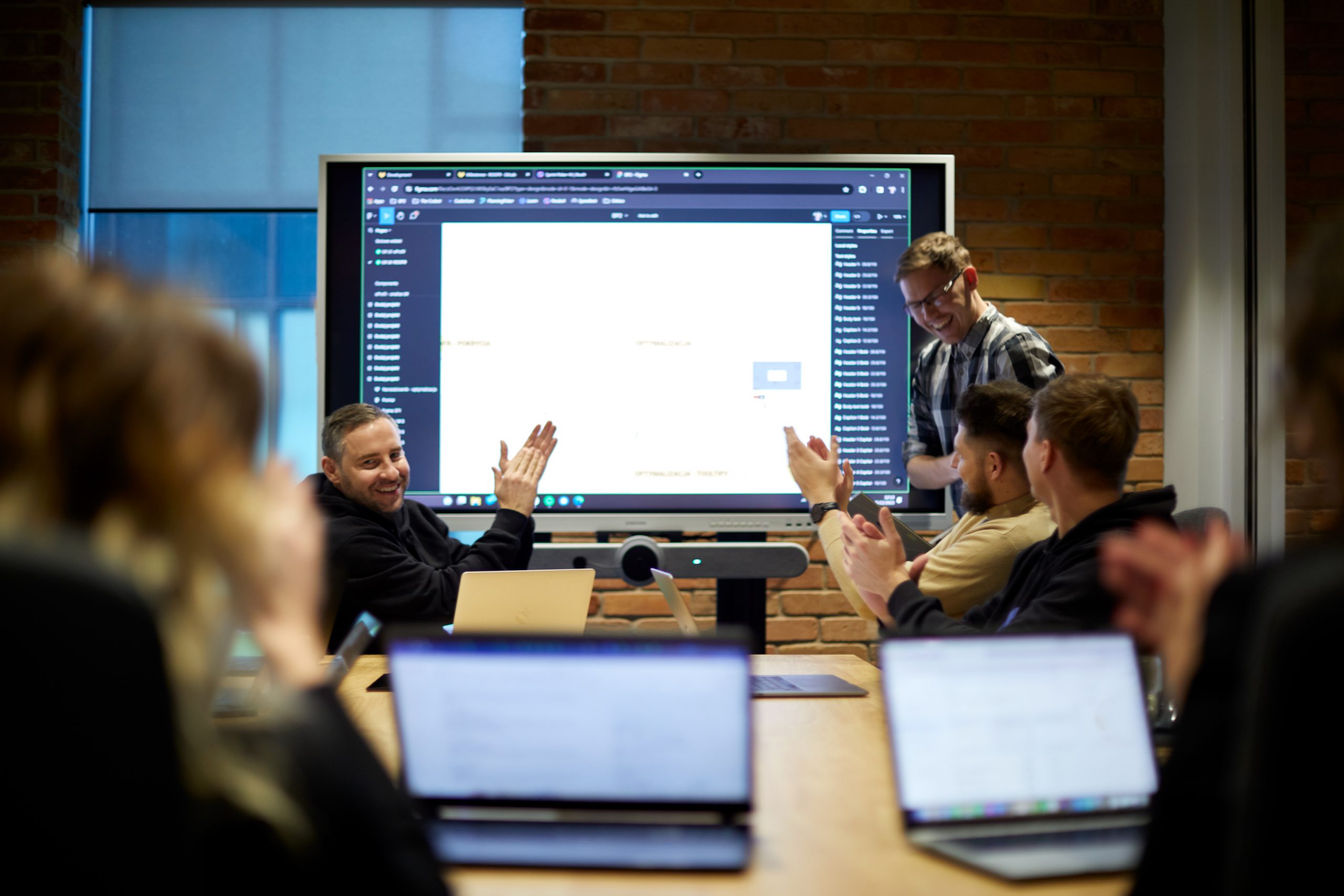 group of people in front of a big screen