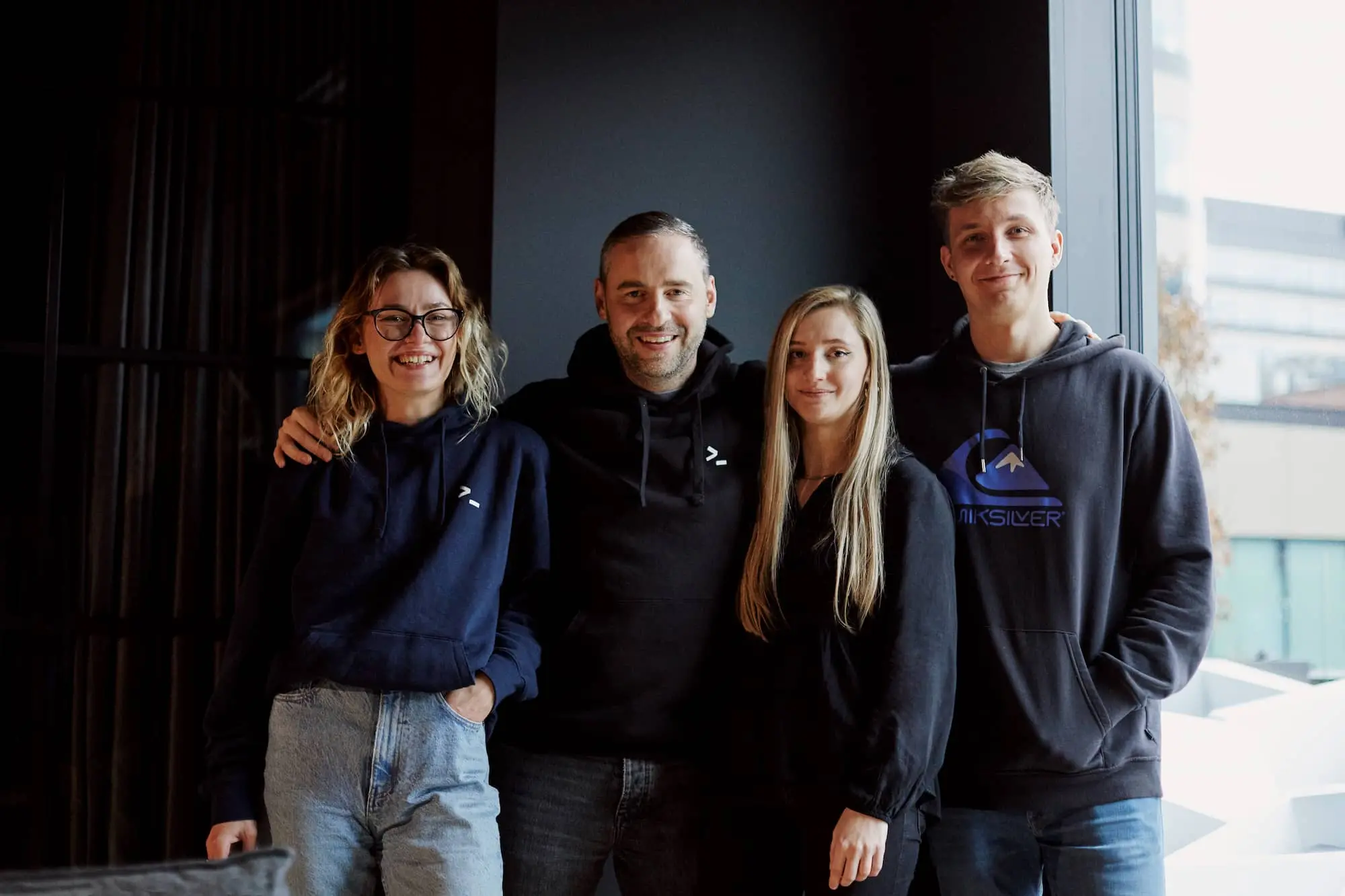 Smiling team members posing together in casual attire inside a modern office.